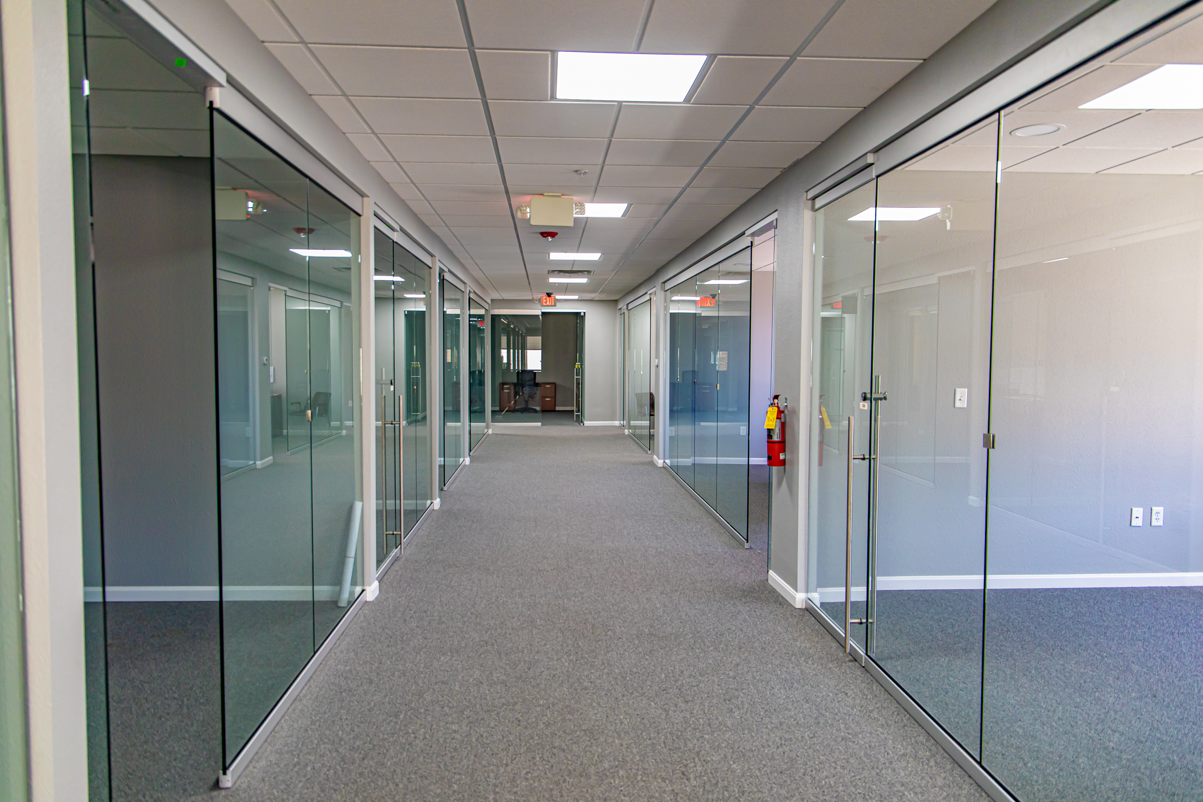 A corridor lined with glass-fronted office spaces inside 700 Market Street.