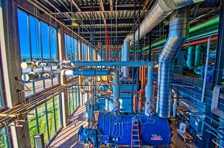 Pipes, ductwork and equipment inside a large building mechanical room.