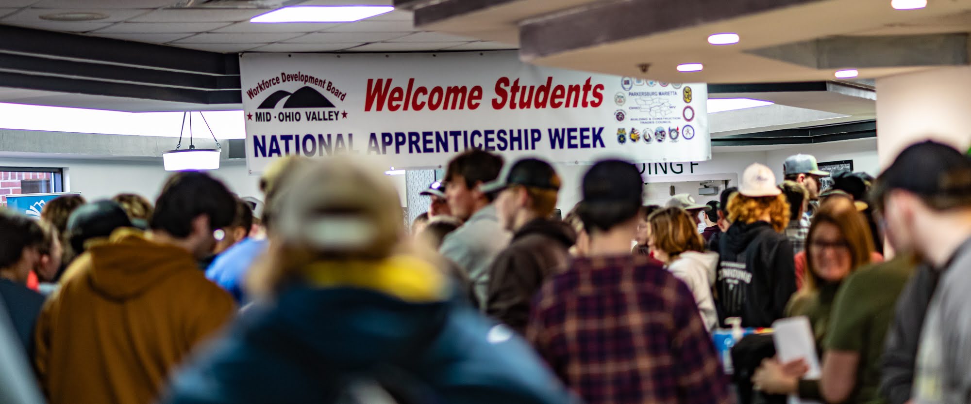 Students and visitors gather beneath a National Apprenticeship Week banner during an event at St. Joseph.